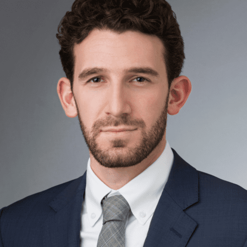 Zack Goldberg short brown hair, wearing a blue blazer, white shirt and gray tie